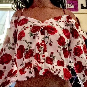 A floral, long sleeve off shoulder, white crop with red roses over it
